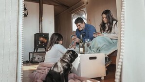 A cozy indoor setting with a wood-burning stove, a dog, and people playing cards. - AfriCamps at Stanford Hills Estate- Glamping (Stanford)