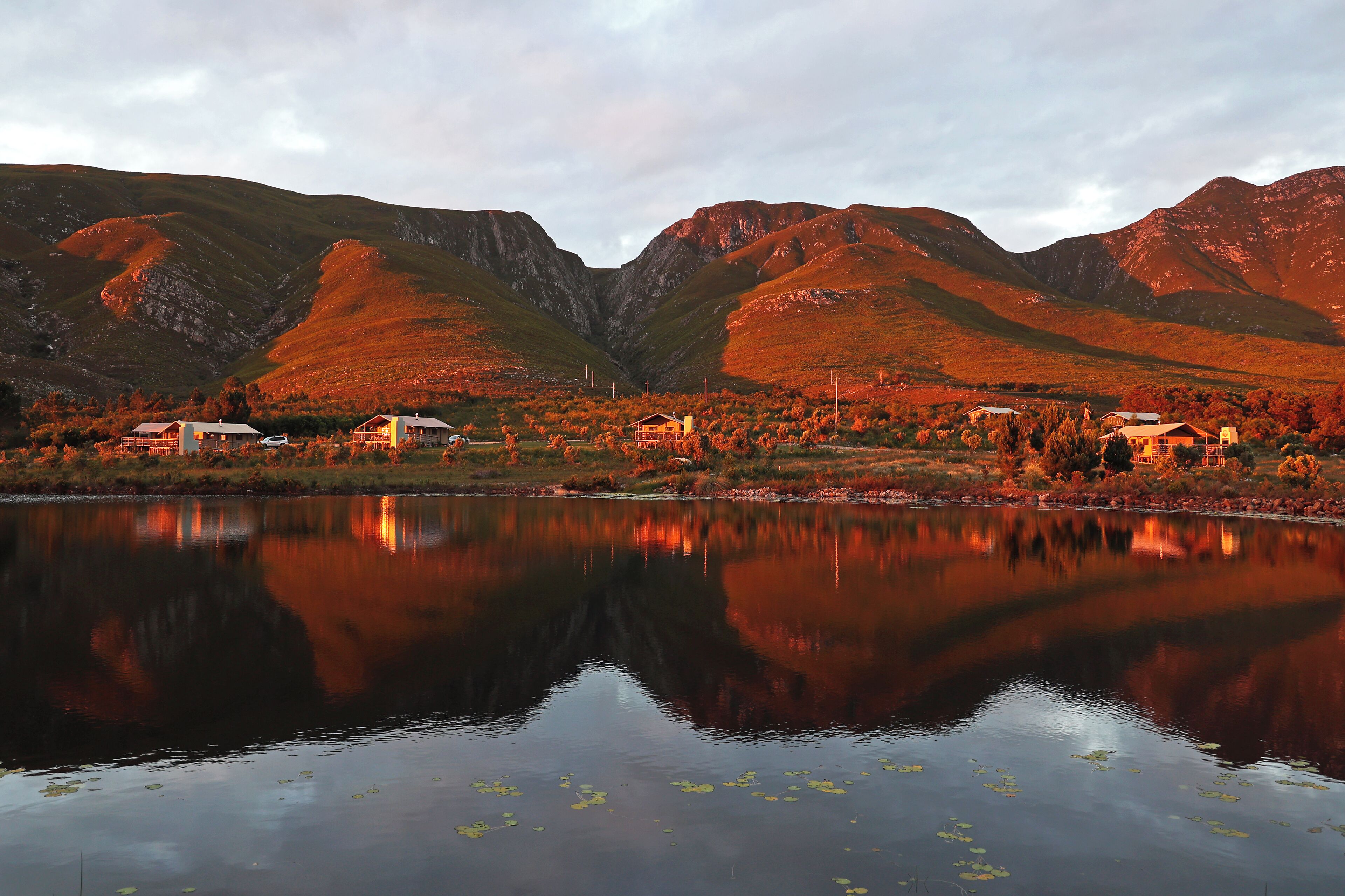 A lake with reflections of mountains and houses.