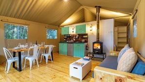 A cozy tent-style accommodation with a dining area, kitchenette, and a wood-burning stove. - AfriCamps at Stanford Hills Estate- Glamping (Stanford)