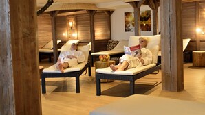 A spa area with two lounge chairs, wooden beams, and a small table with a bowl of fruit. - Burg Hotel (Feldberg)