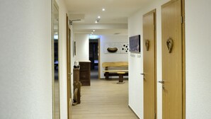 A hallway with wooden doors, a bench, and a wall-mounted artwork. - Burg Hotel (Feldberg)