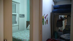 A bedroom with a bed, a window, a wall with a picture, and a closet with hanging items. - Copacabana Guest House (Rio de Janeiro)