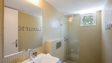 Baño con lavamanos, espejo y ducha.