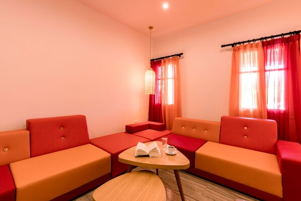 A room with two red sofas, a small table with a book and a cup, and a hanging light fixture.