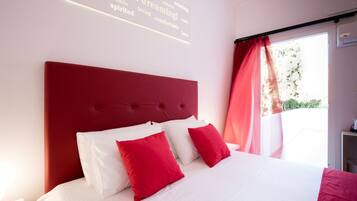 A bedroom with a red headboard, white bedding, and a window with curtains.
