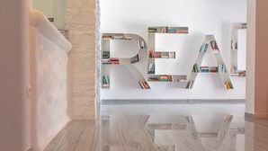 Un interior moderno con piso pulido y una pared blanca con una estantería con forma de la letra 'R'.