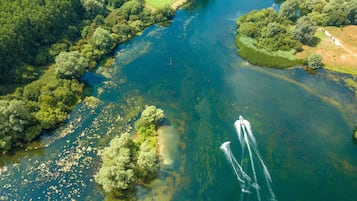 Vista aérea de um rio com barcos, cercado por vegetação densa e árvores.