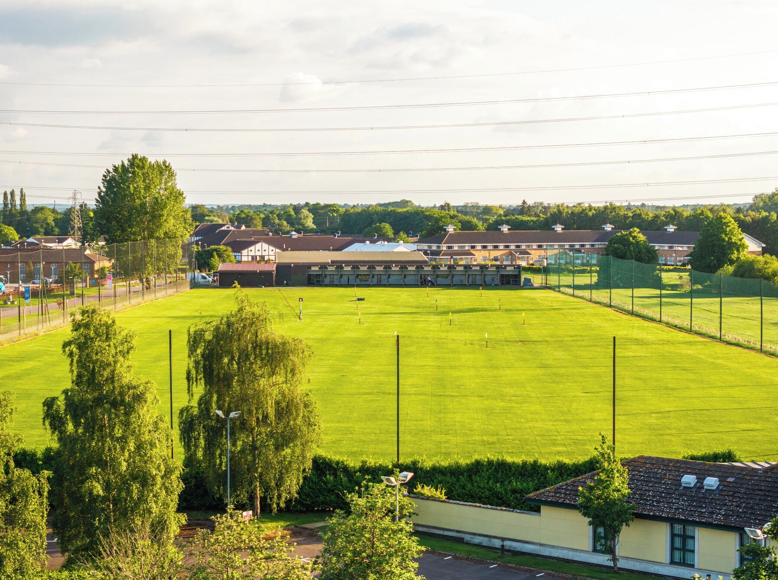 A large, well-maintained grassy field with a building in the background.