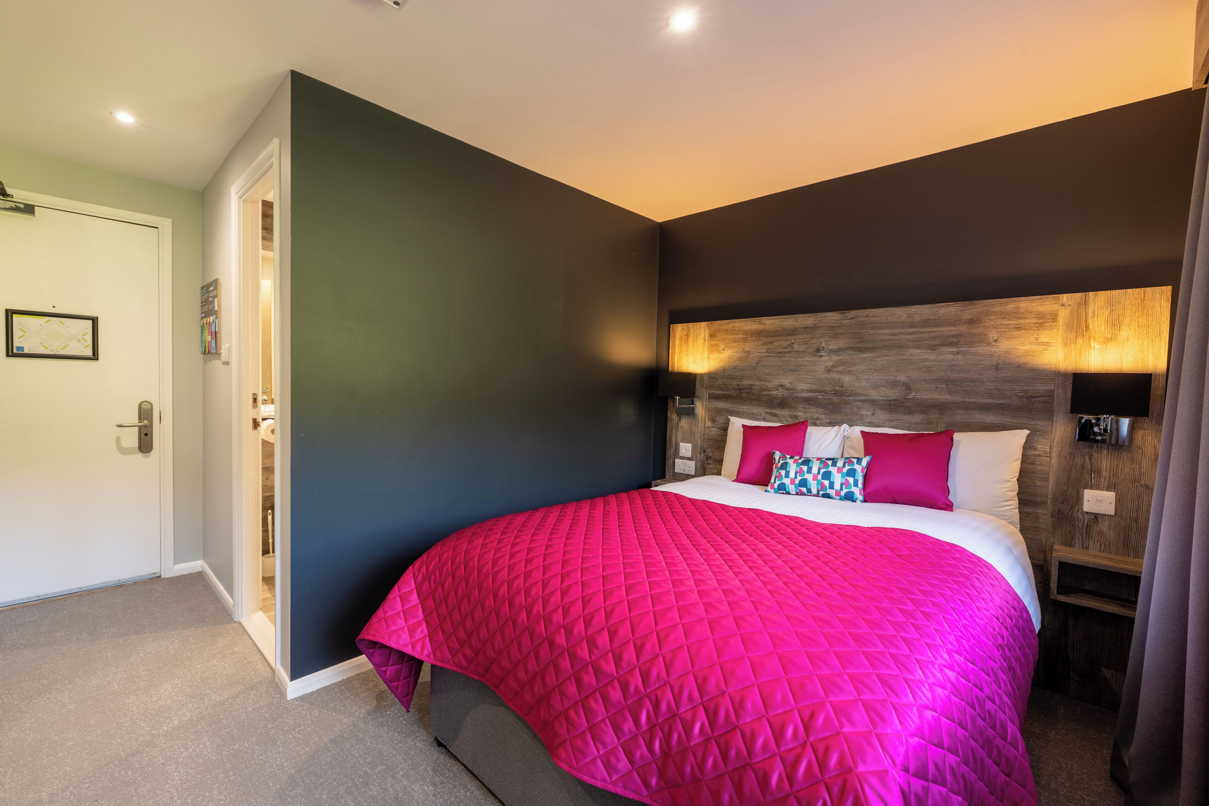 A bedroom with a large bed, dark walls, and a wooden headboard.
