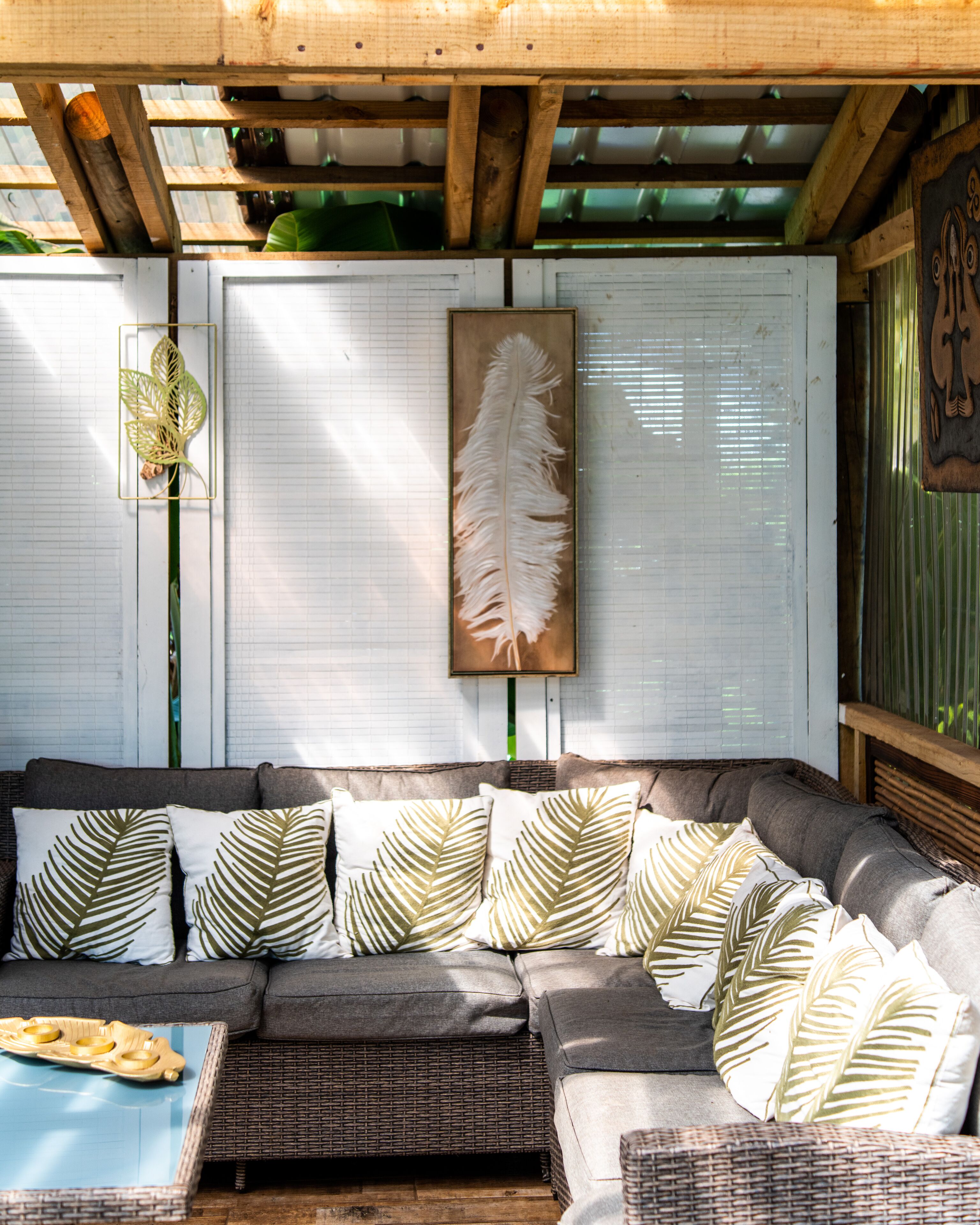 A cozy outdoor seating area with a cushioned sofa, patterned cushions, and a wooden table.