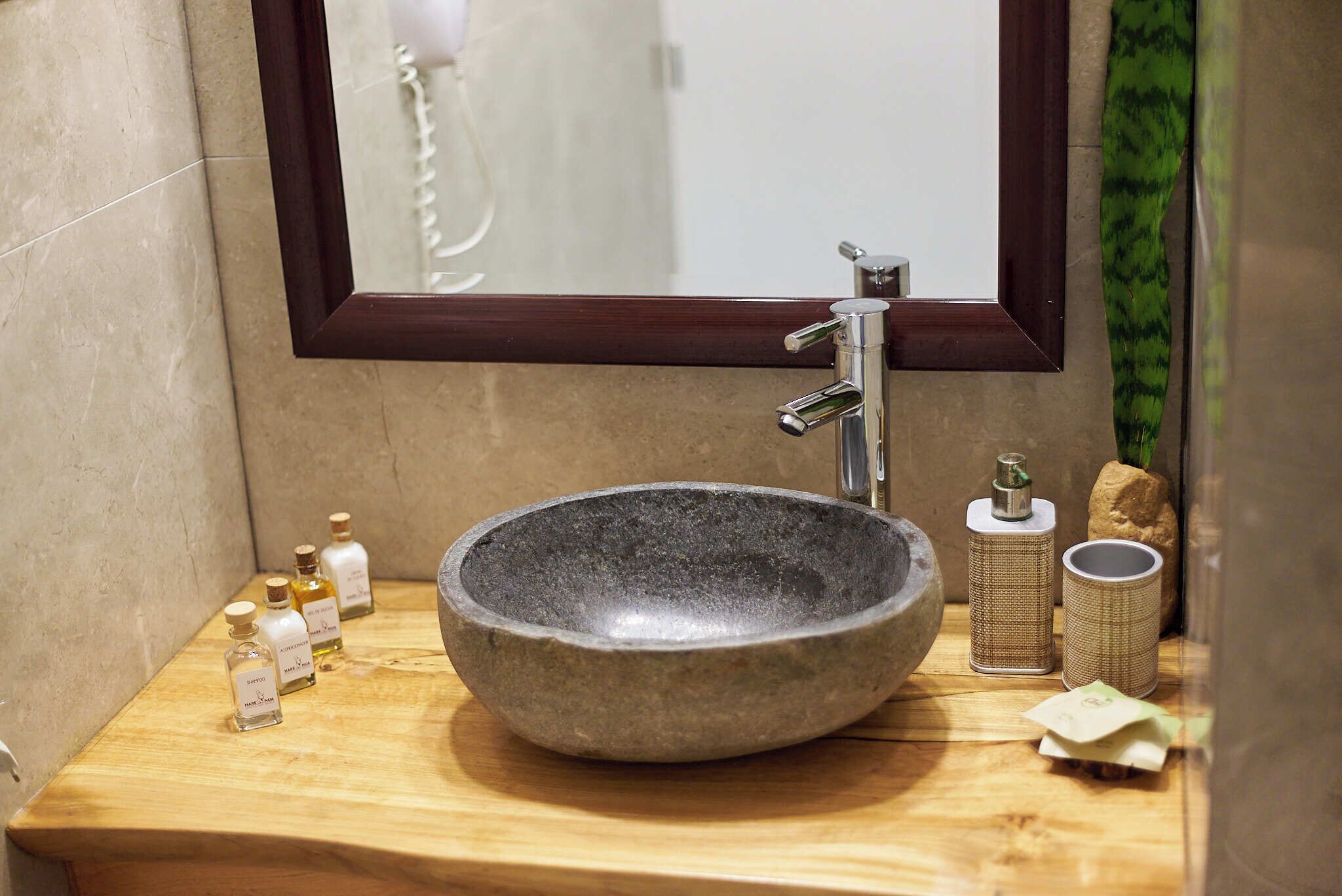 Une salle de bain avec un lavabo en pierre, un miroir et des articles de toilette posés sur le comptoir.