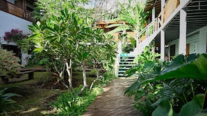 A wooden pathway leading to a building with a wooden balcony and lush greenery. - Hare Nua (Hanga Roa)