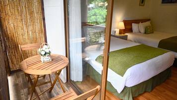 Une chambre d’hôtel avec un lit, une petite table avec des chaises et une vue sur la verdure.