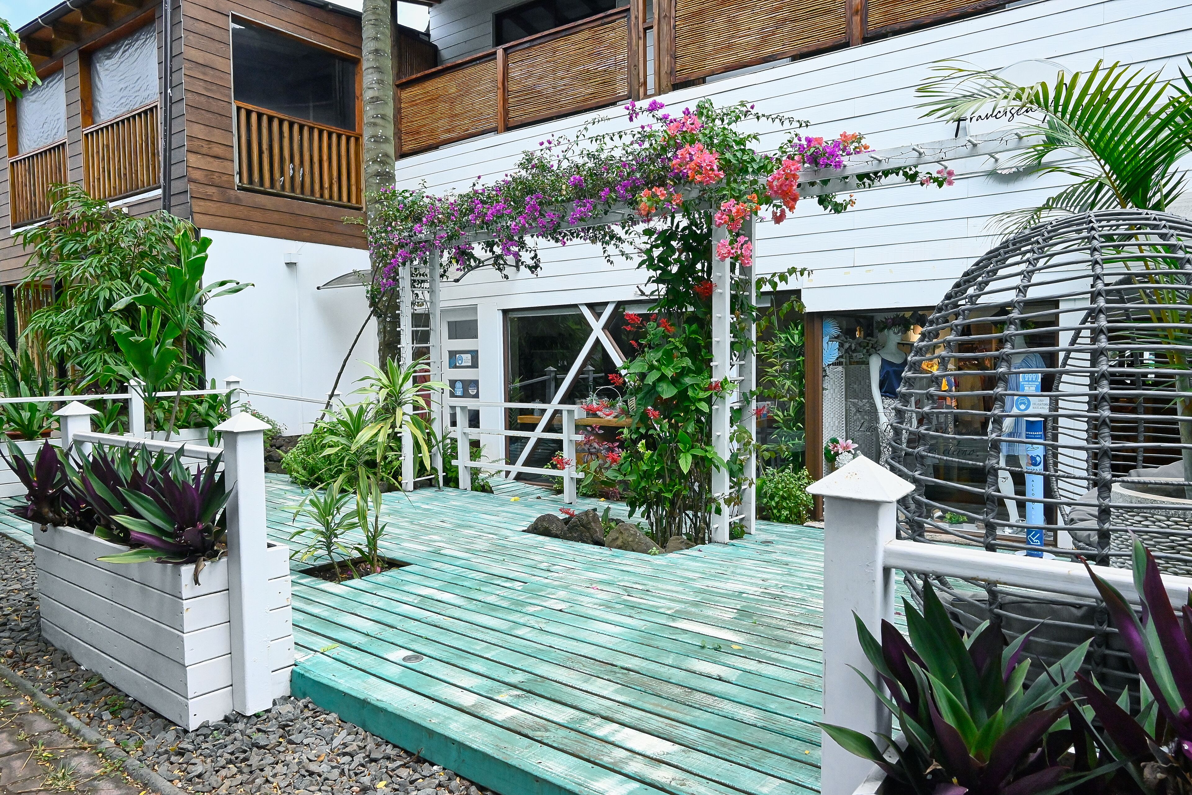 A modern building with a wooden balcony, a white fence, and a wooden deck with plants.