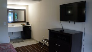 A hotel room with a bed, a TV mounted on the wall, a small kitchenette with a sink, and a mirror above the counter. - Best Stay Inn (Plainville)