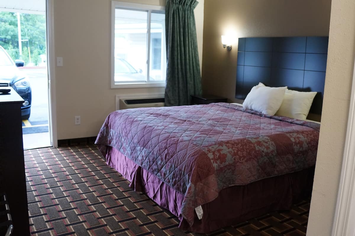 Une chambre d’hôtel avec un lit, un bureau, une fenêtre avec des rideaux et une vue sur l’extérieur.