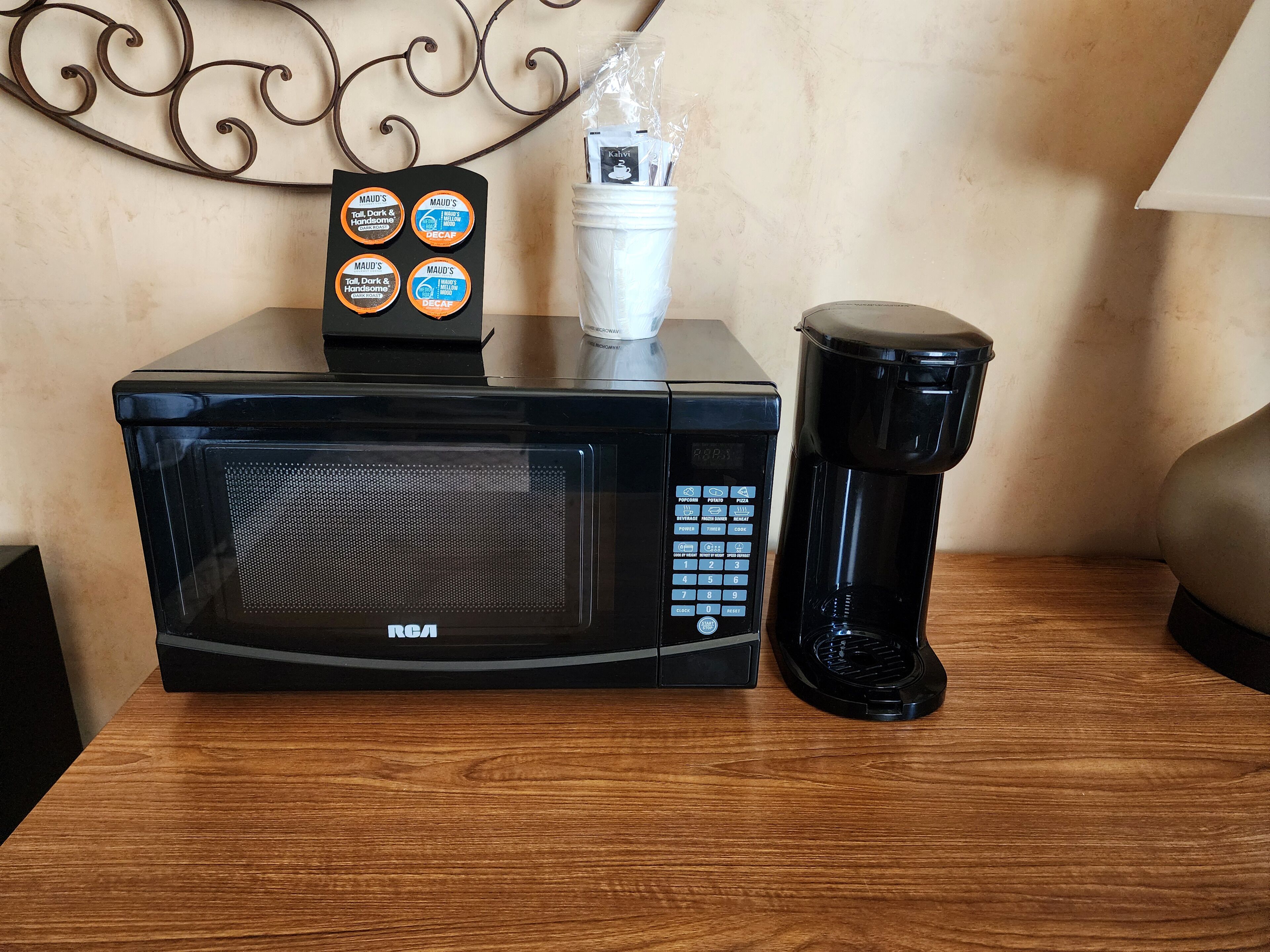 Een zwarte R64 magnetron op een houten tafel, met een zwarte koffiezetapparaat ernaast.