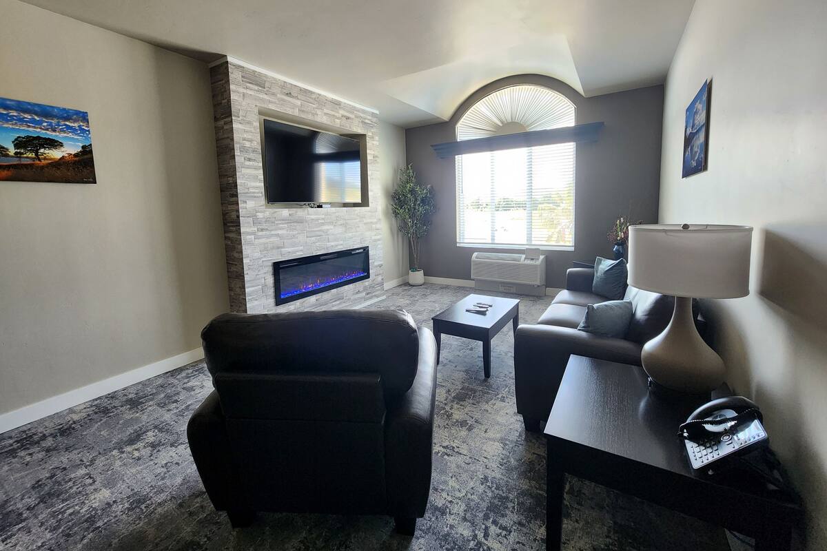 A living room with a stone fireplace, a flat-screen TV, a sofa, a coffee table, and a lamp.