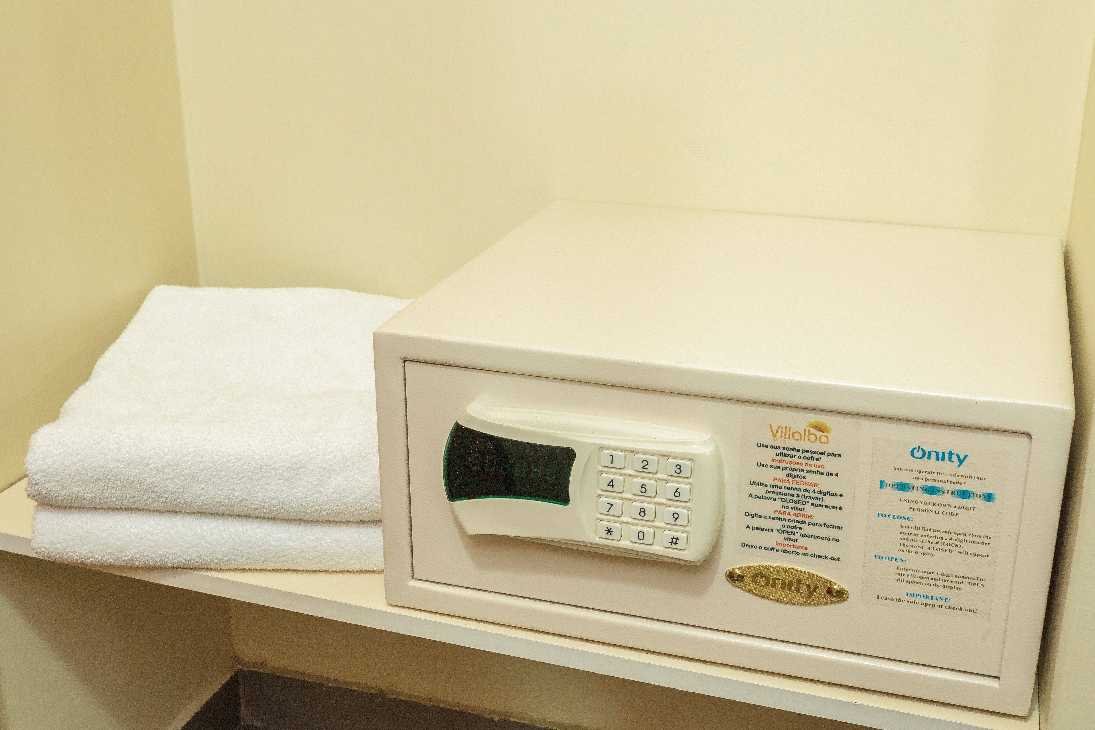 A white towel on a shelf next to a white electronic device with a keypad and screen, possibly a control panel or security device.