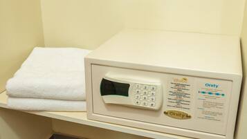 A white towel on a shelf next to a white electronic device with a keypad and screen, possibly a control panel or security device.