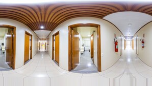 A long, polished hallway with wooden doors and white tiled floors. - Villalba Hoteis (Londrina)