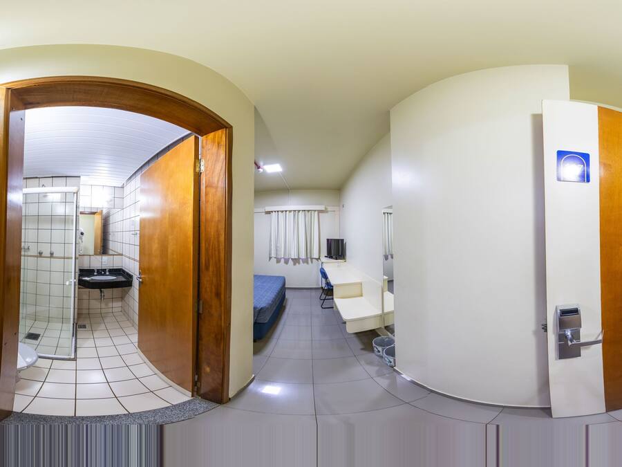 Pasillo de hotel con un baño, una cama y un espacio de trabajo.