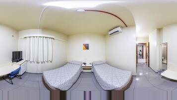 A clinical room with two beds, a desk with a chair, a TV, and an air conditioning unit.