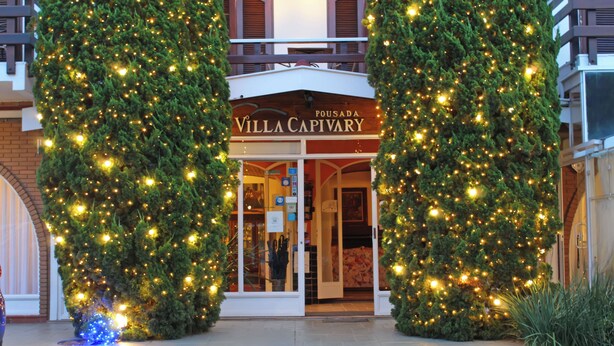 Entrada de un hotel con un letrero que dice "Villa Capivary" y un árbol de Navidad con luces.
