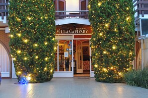 A hotel entrance with a sign reading "Villa Capivary" and a Christmas tree with lights.
