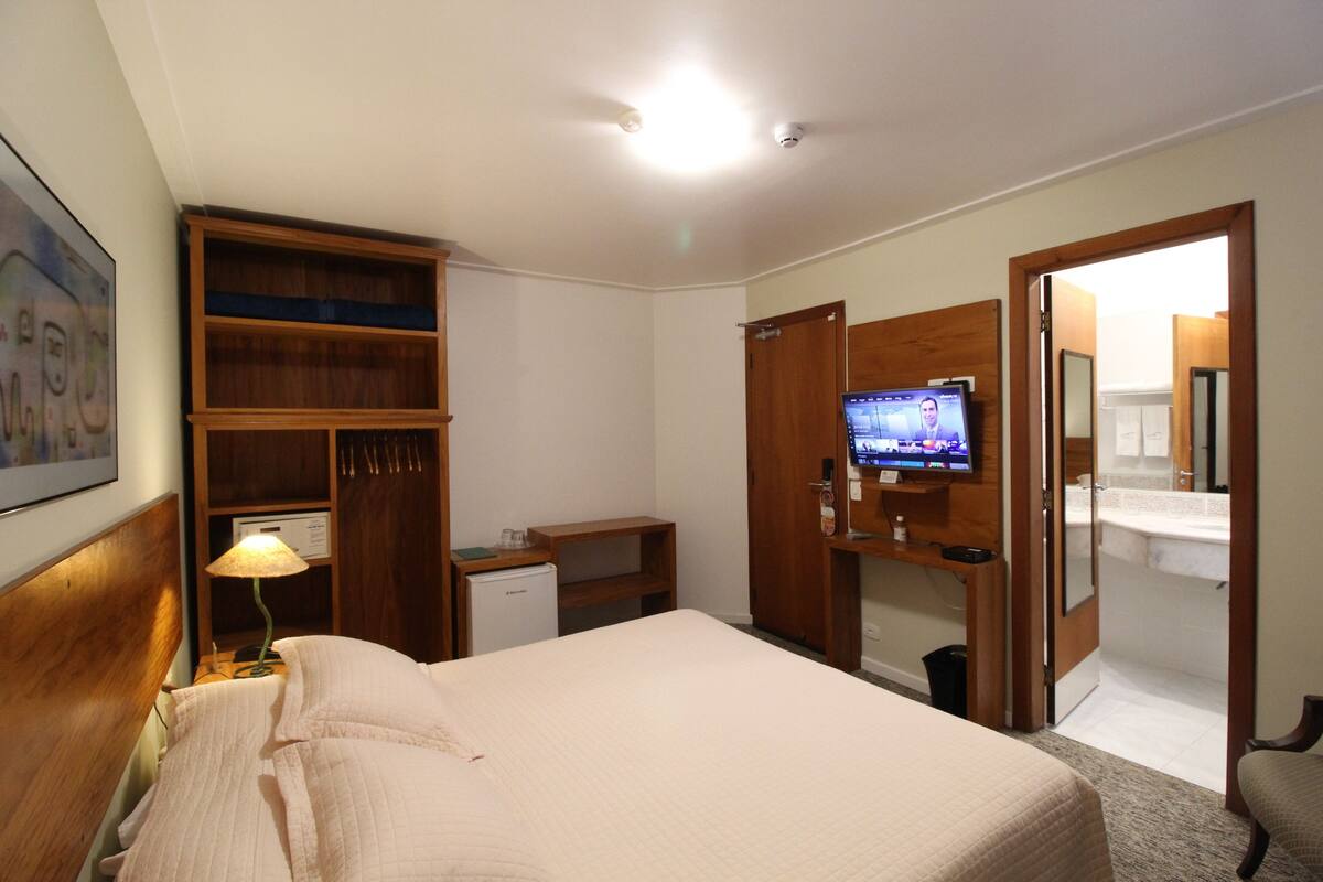 Une chambre d’hôtel équipée d’un lit, d’une télévision, d’un bureau et d’une armoire.