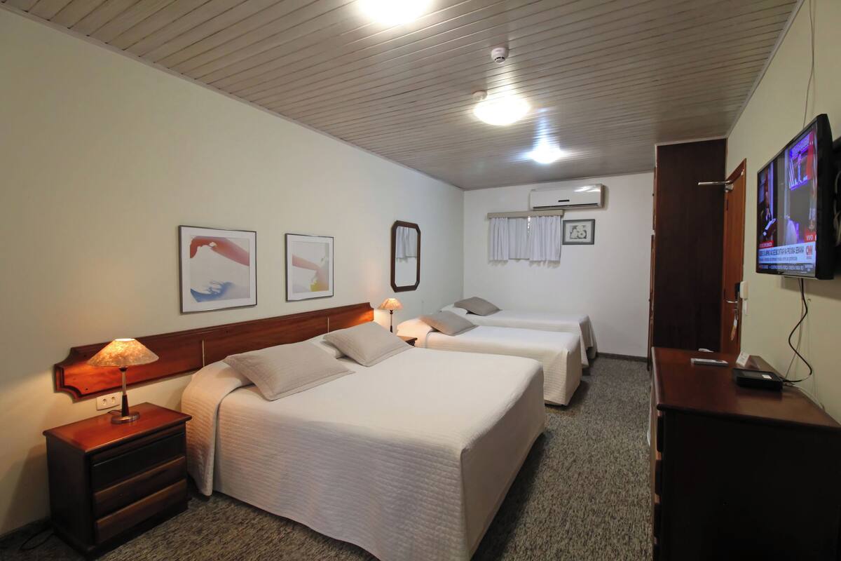 Une chambre d’hôtel avec deux lits, une télévision, un bureau et une table de chevet avec des lampes.