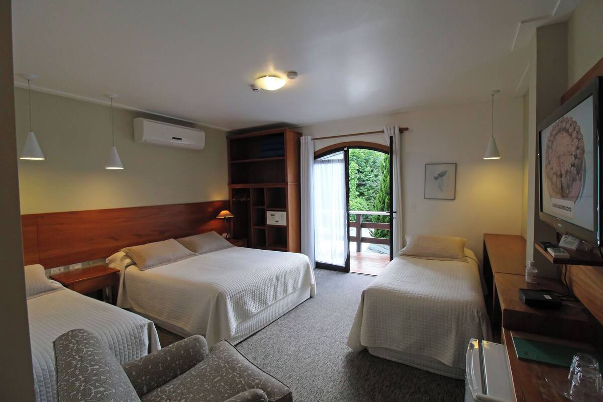 Une chambre d’hôtel avec deux lits, un bureau, une chaise, une télévision et une vue sur l’extérieur.