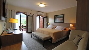 Una habitación de hotel con cama, escritorio, silla, banco y televisor.