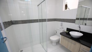 Ein modernes Badezimmer mit Duschkabine aus Glas, einer weißen Toilette und einer schwarzen Ablage mit Waschbecken.