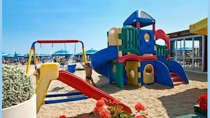 Un parque infantil en la playa con toboganes y estructuras para escalar.