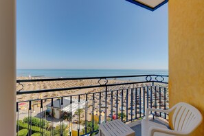 A balcony with a view of a beach, white chairs, and a railing. - Hotel Napoleon (Jesolo)