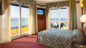 Una camera d'hotel con un letto grande, una televisione e un balcone vista mare.