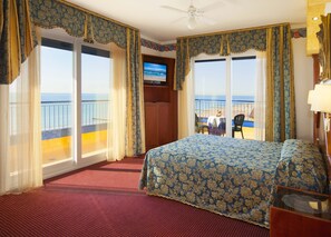 A hotel room with a large bed, a TV, and a balcony with a view of the sea. - Hotel Napoleon (Jesolo)