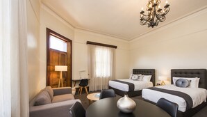 Una habitación de hotel con dos camas, un sofá, una mesa de comedor y un candelabro.