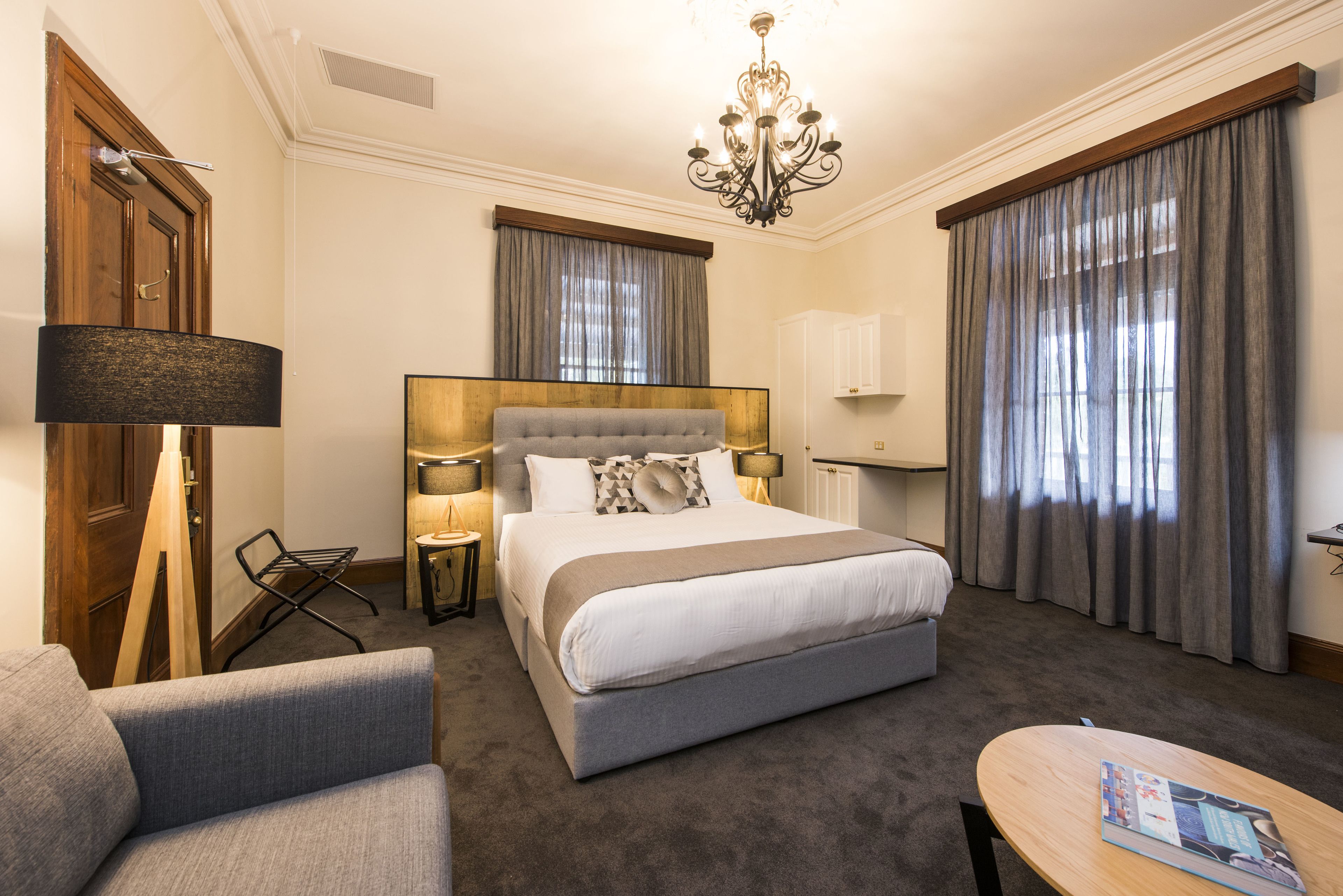 Ein Hotelzimmer mit einem großen Bett, einer Sitzecke mit einem Sessel, einem kleinen Tisch und einer Chandelier.
