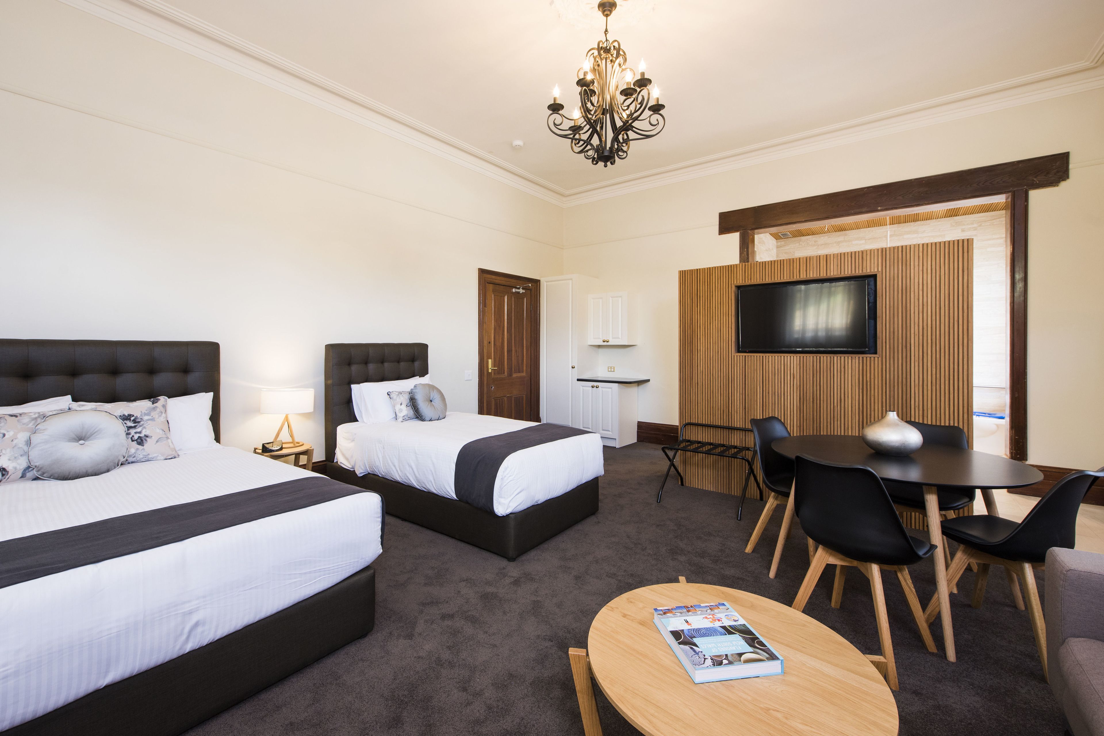 A hotel room with two beds, a TV, a dining table, and a coffee table.