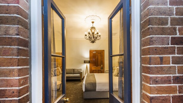 Una habitación de hotel con una cama grande, un rincón de estar con sofá y un candelabro.
