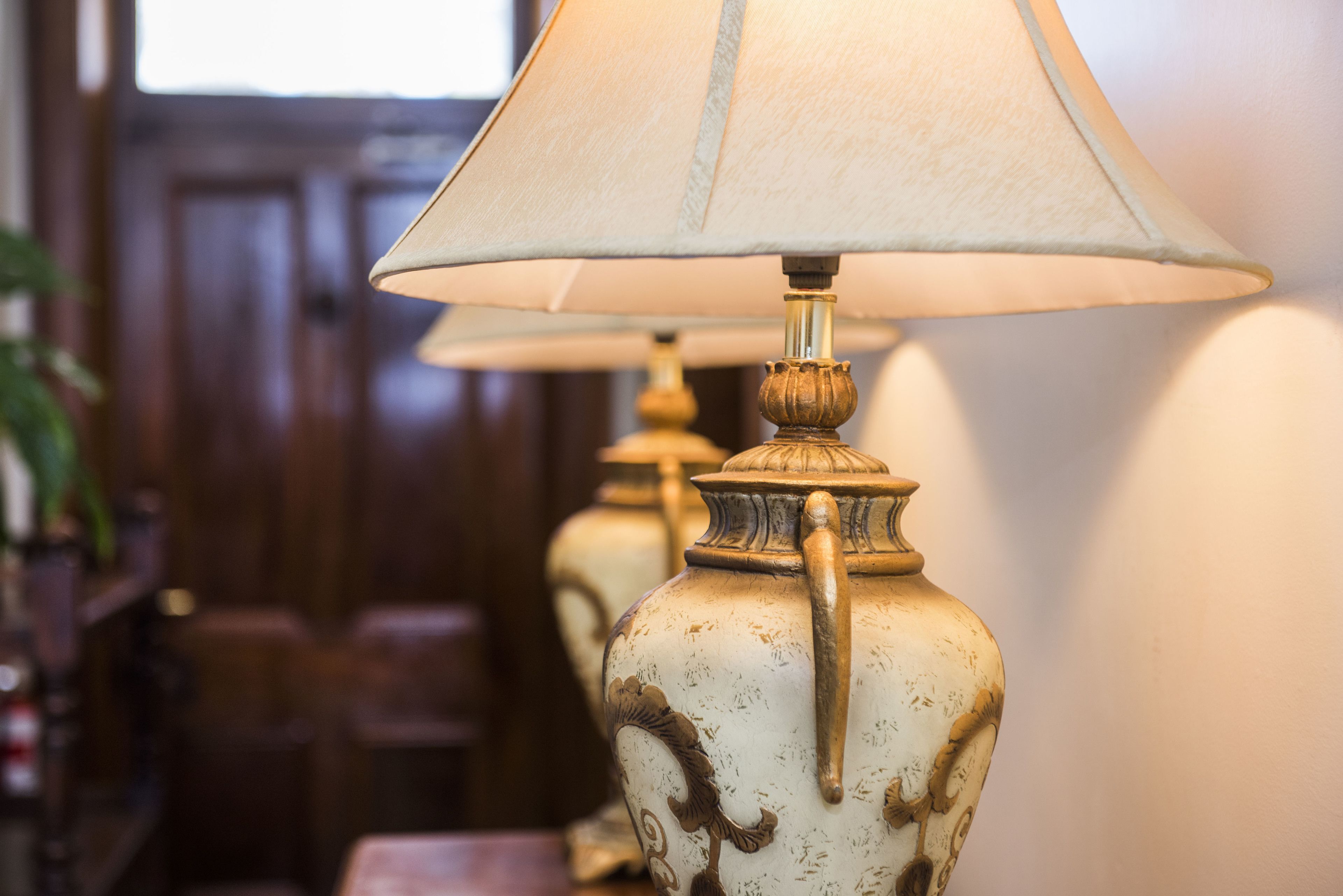 A series of vintage-style lamps with a classic design, positioned on a wooden floor against a plain wall.