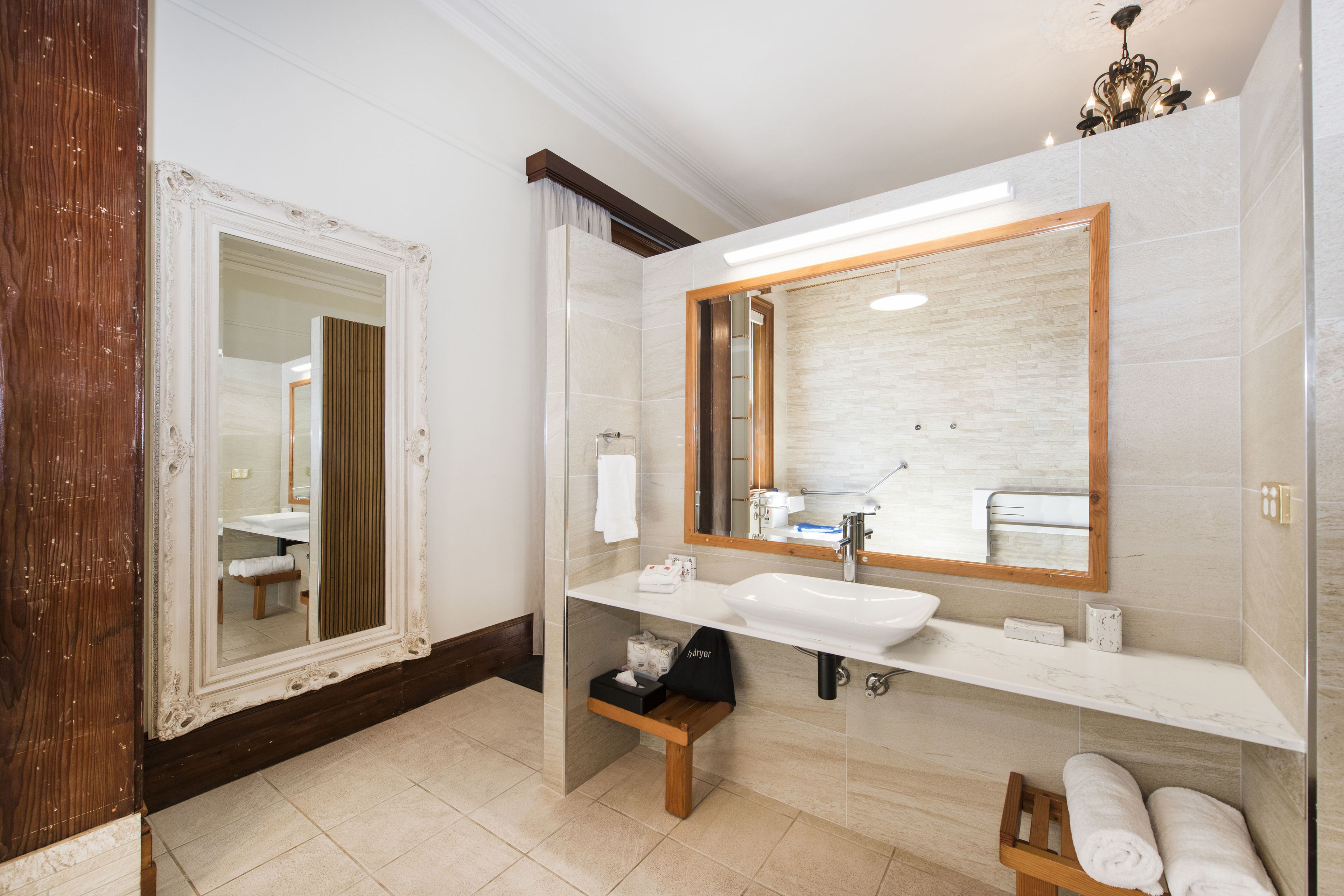 Un bagno moderno con uno specchio grande, un lavandino bianco e una panca in legno.