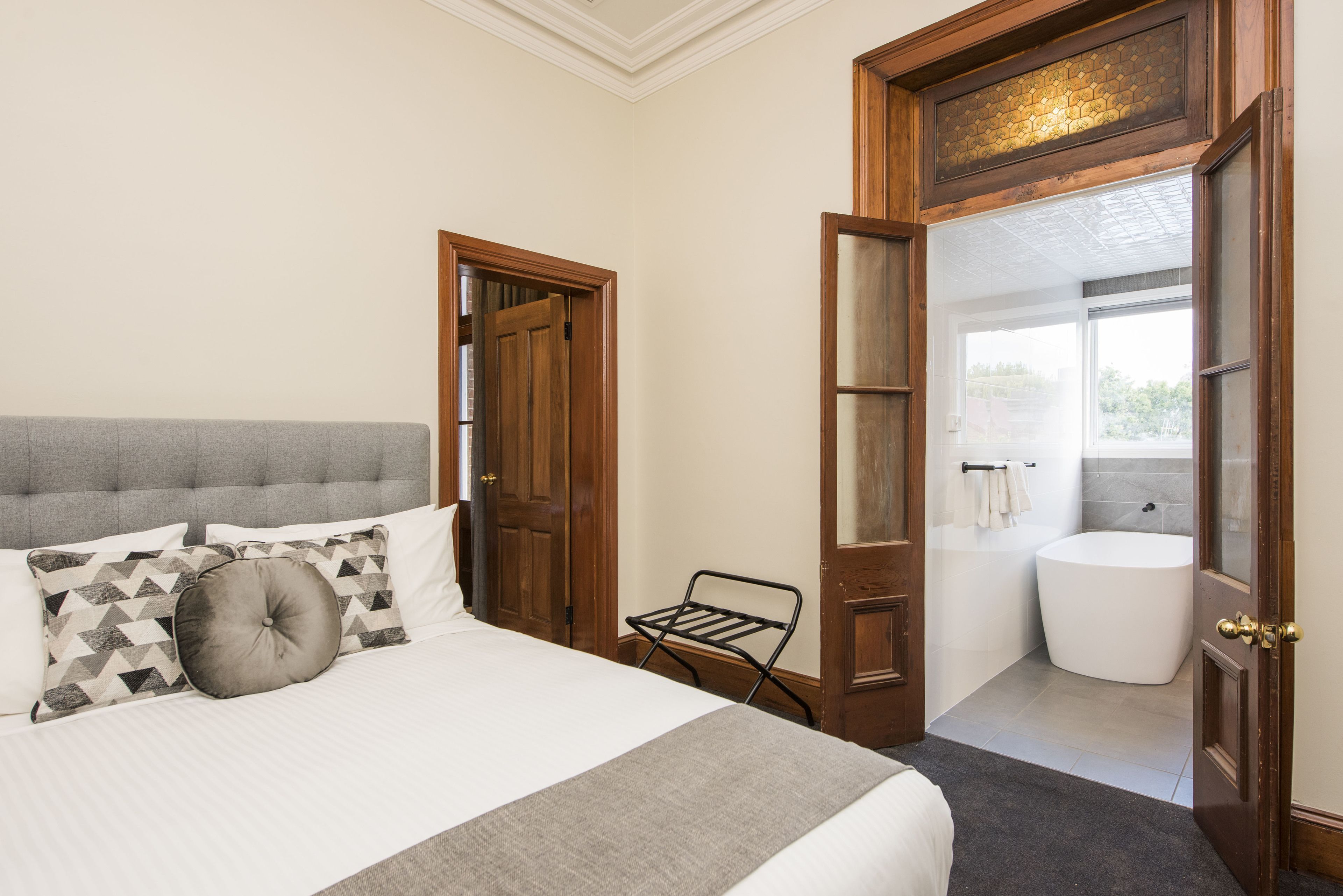 Un dormitorio con cama, una puerta de madera y vistas a un baño con bañera.