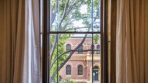 Una ventana con vistas a un edificio de ladrillo y una rama de árbol.