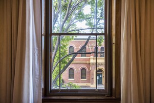 Una ventana con vistas a un edificio de ladrillo y una rama de árbol.