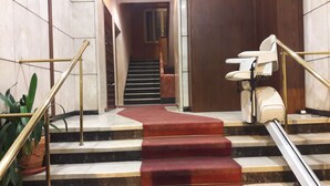 Un escalier recouvert d’un tapis rouge, avec des marches en marbre et une main courante.