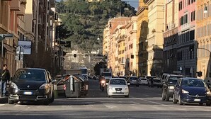 Une vue de rue avec des bâtiments de chaque côté, un feu de signalisation et une colline sur laquelle se trouve une construction au loin.