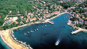 An aerial view of a coastal town with a marina, boats, and residential buildings.